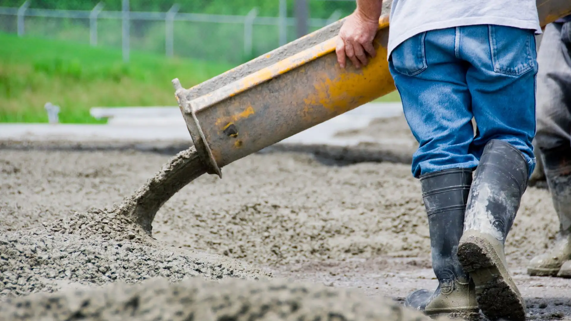 A construction worker spreading cement from a cement mixer