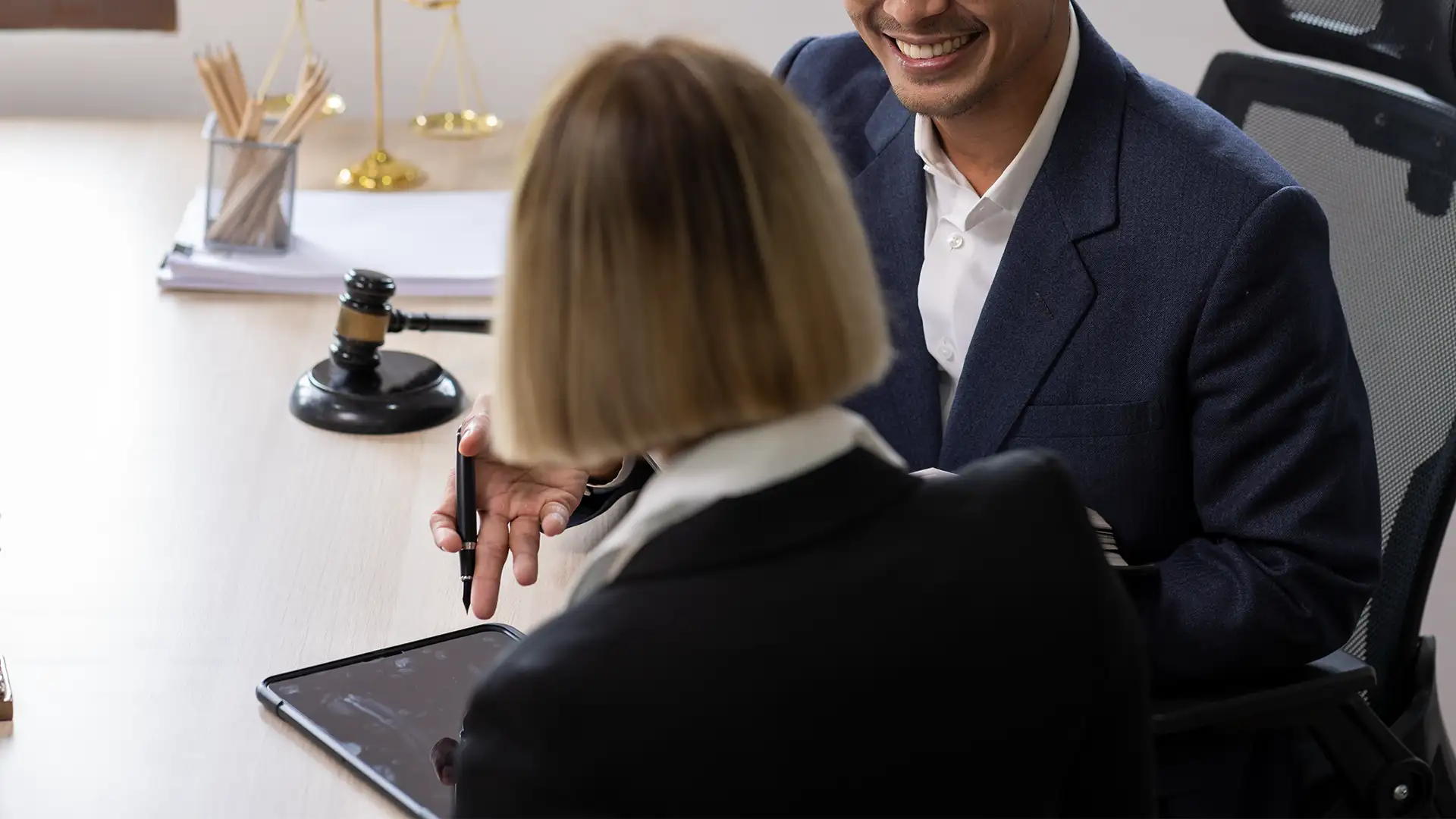 Attorney and client sitting at desk reviewing tablet and document