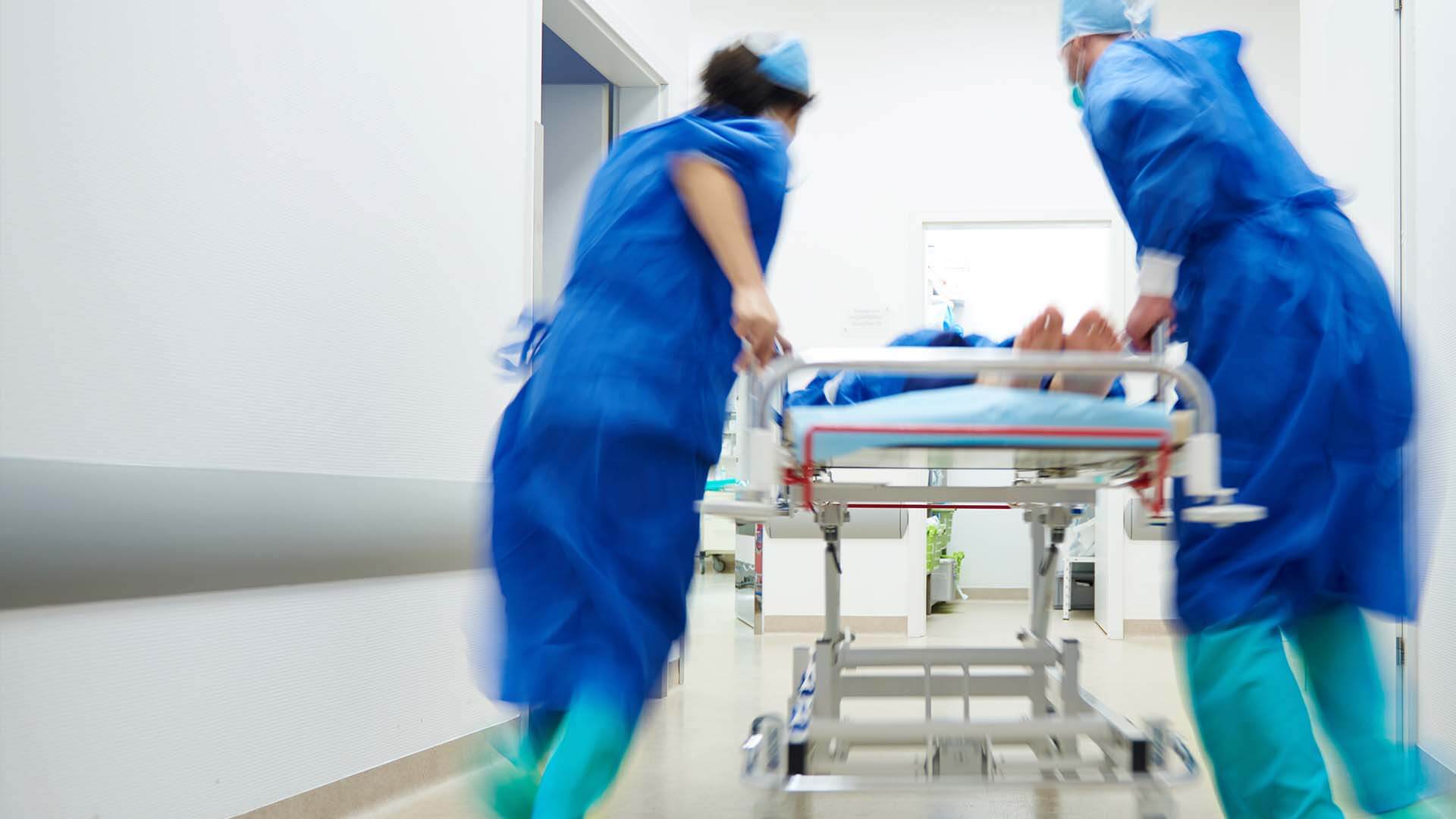 Doctors rushing a personal injury victim that has suffered a degloving injury on a stretcher into the emergency operating room
