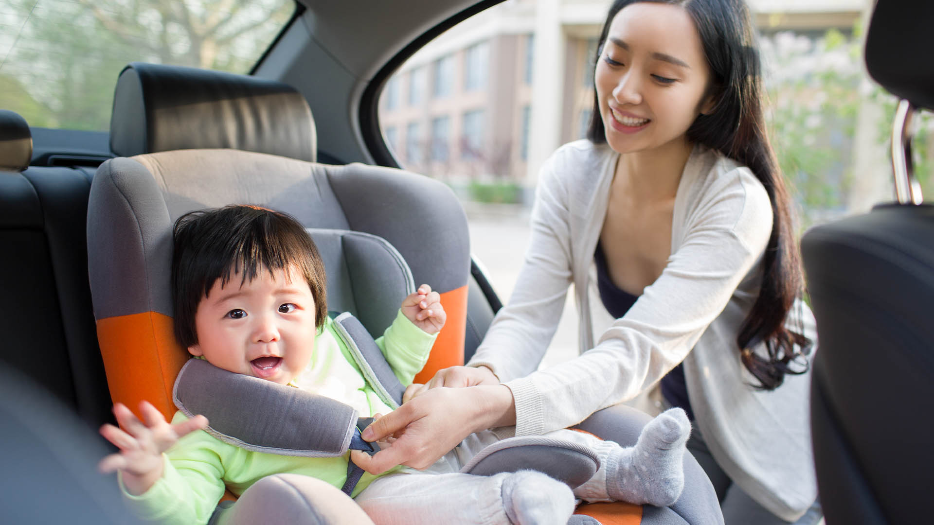 A mother fastening her child into a car seat