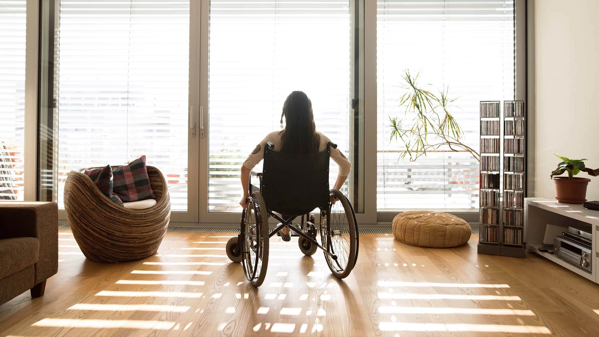 A young woman sits in a wheelchair in her home after suffering spinal cord injury caused by an accident
