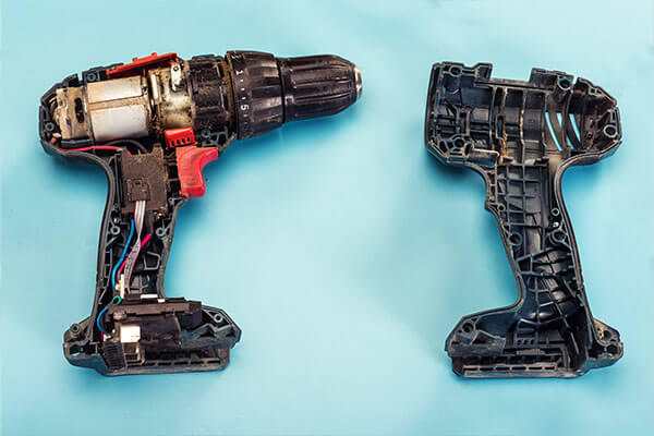 A disassembled cordless power drill that is dirty and could be potentially be a dangerous or defective product