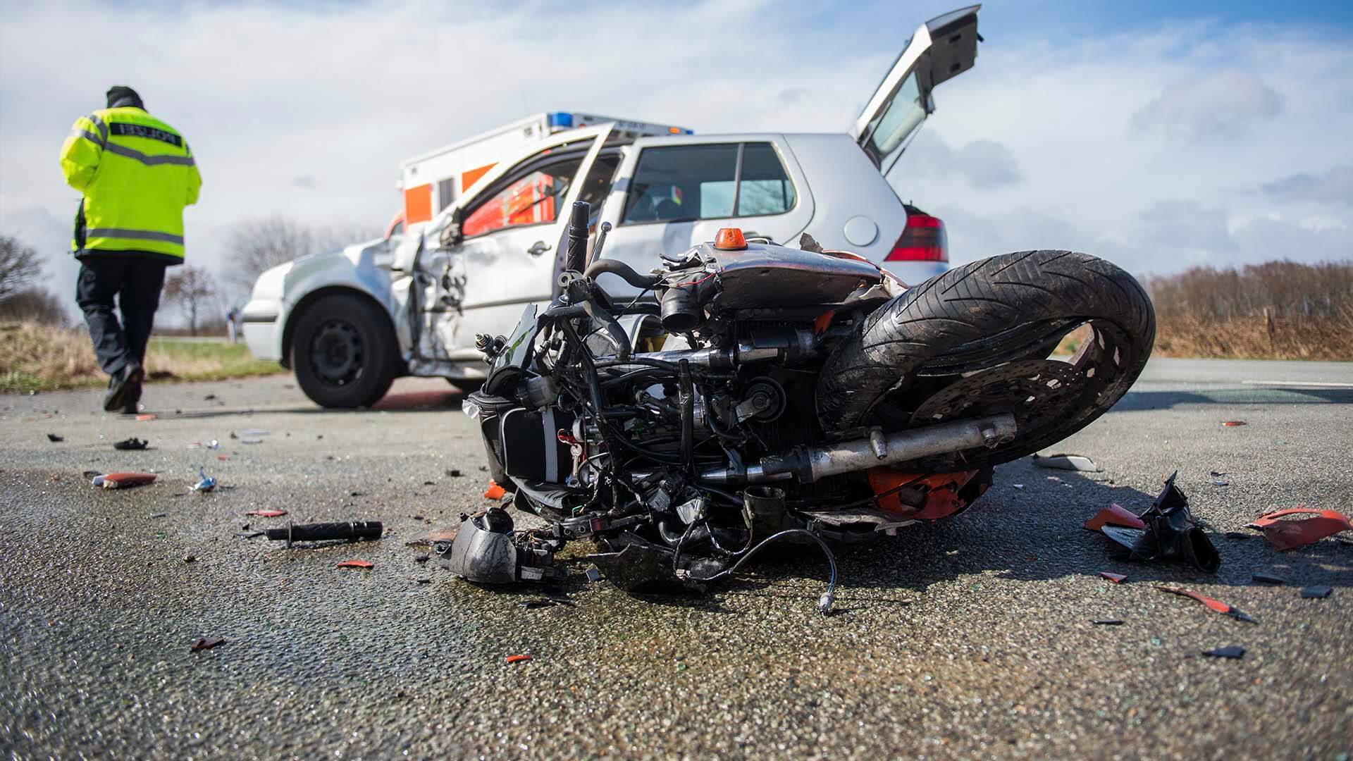 A destroyed motorcyle laying on road after being involved in a car accident